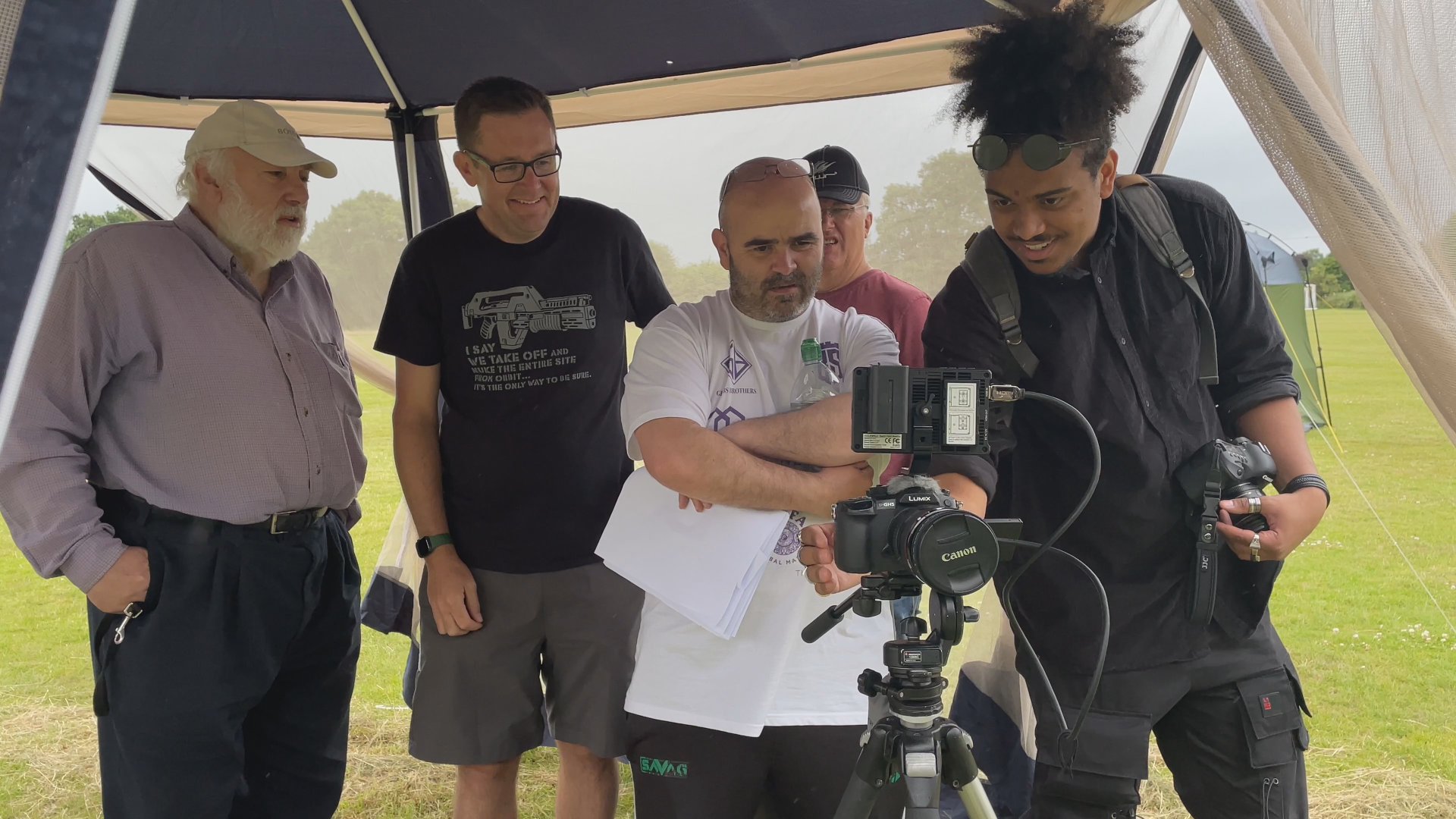A photo of Kyle Simms operating a camera surrounded by crew, outdoors